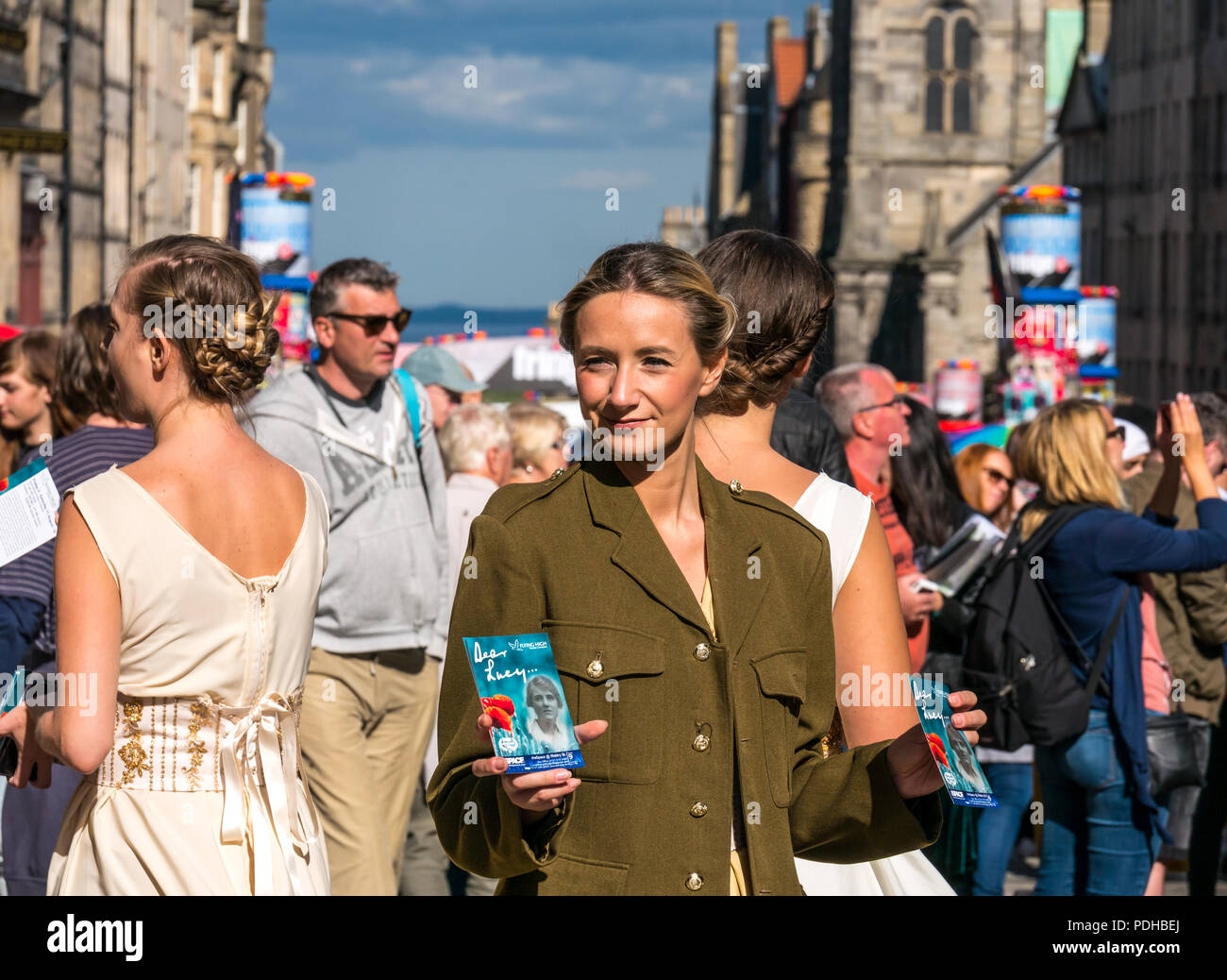Edinburgh, Scotland, UK. 9th August 2018. Edinburgh Fringe Festival, Royal Mile, Edinburgh, Scotland, United Kingdom. On a sunny festival day the Virgin Money sponsored street festival is packed with people and fringe performers. A group of pretty young women dressed in World War II era costumes hand out flyers for their Fringe Show called Dear Lucy Stock Photo
