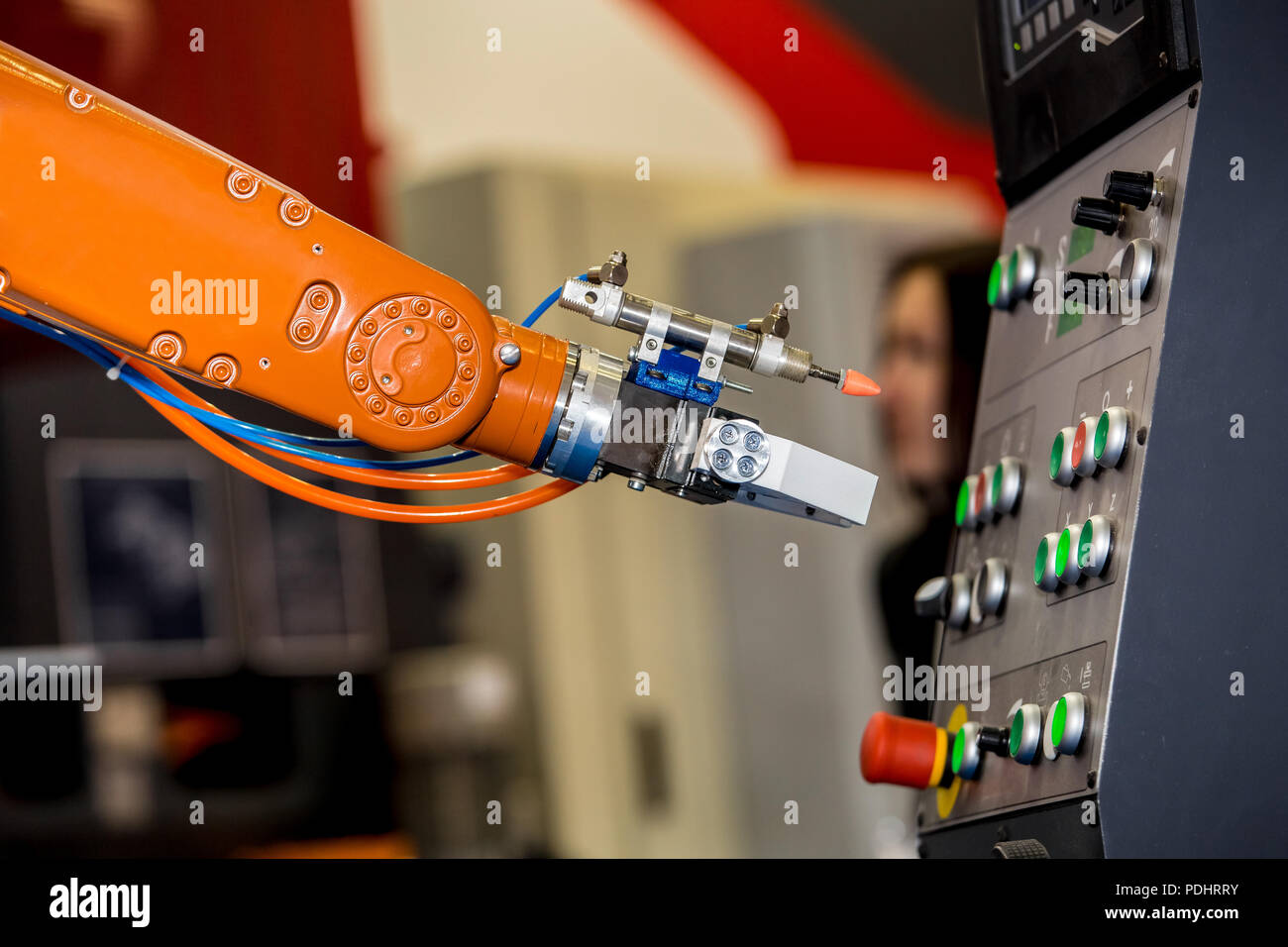 Robot arm pushing the buttons on control panel of CNC machine Stock Photo