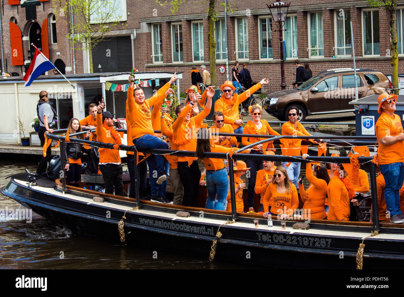 Amsterdam, Netherlands - April, 2018: Boats on Amsterdam canals with people celebrate King's day in Netherlands Stock Photo