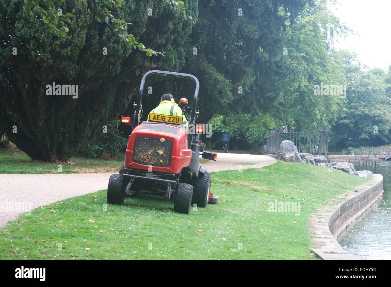 A park worker cuts the grass in pavilion gardens using an industrial mower Stock Photo