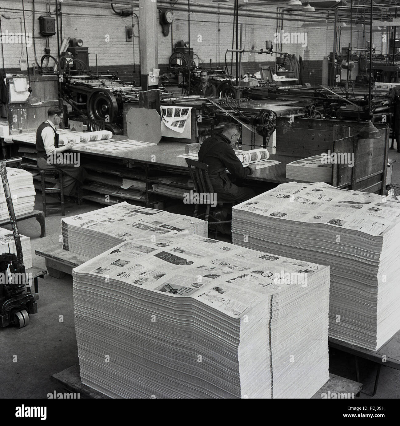 1950s, HWV printers, on the factory floor, checking copies of a recently printed magazine, England, UK. Hazell, Watson & Viney was a long established business which became the British Printing Corporation (BPC) in the 1960s, which in turn was taken over by businessman and former MP, Robert Maxwell in 1981. Stock Photo