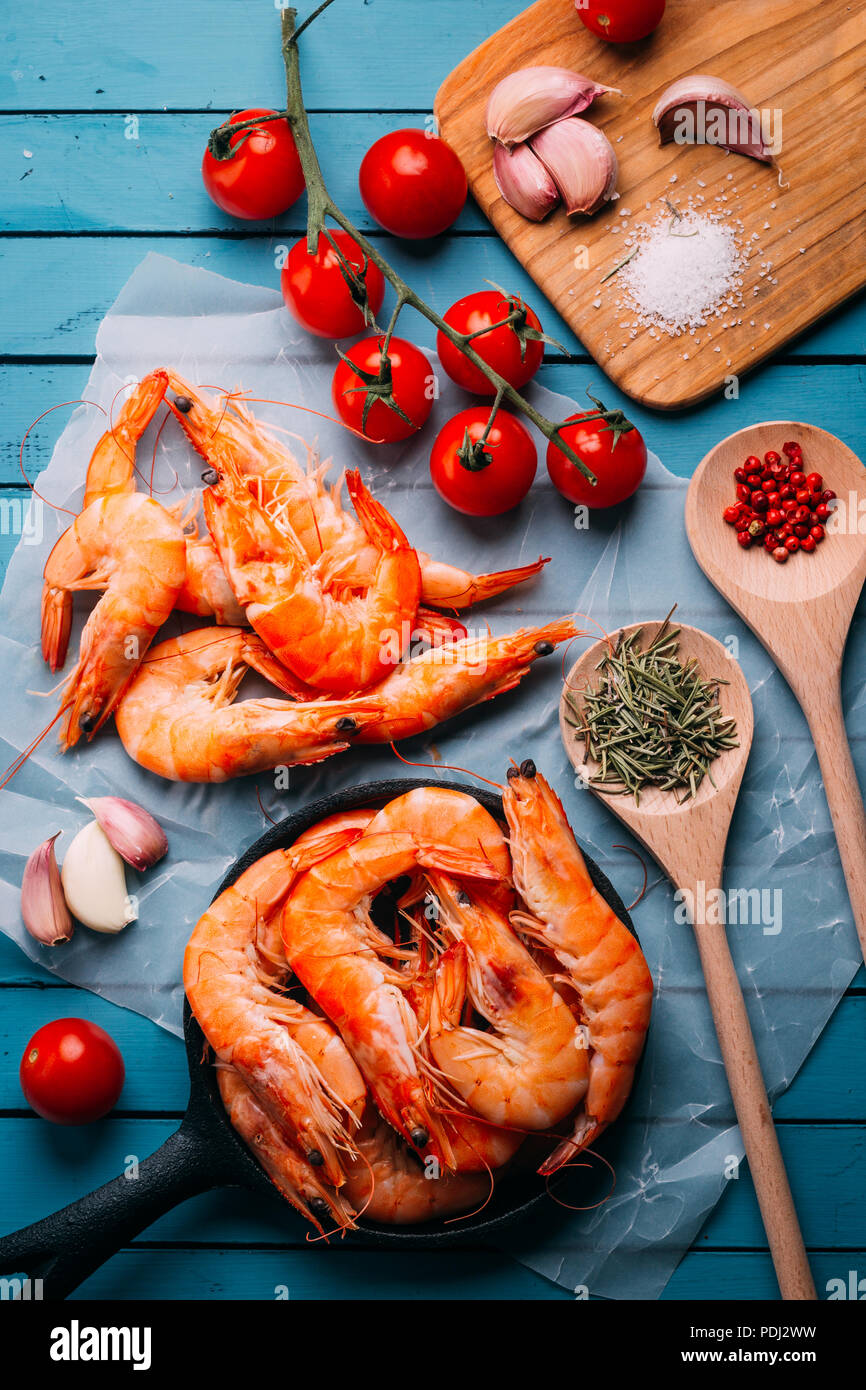 Top view of blue wooden table full of prawns and some ingredients for seasoning and vegetables to mix them, concept of recipes and restaurants Stock Photo