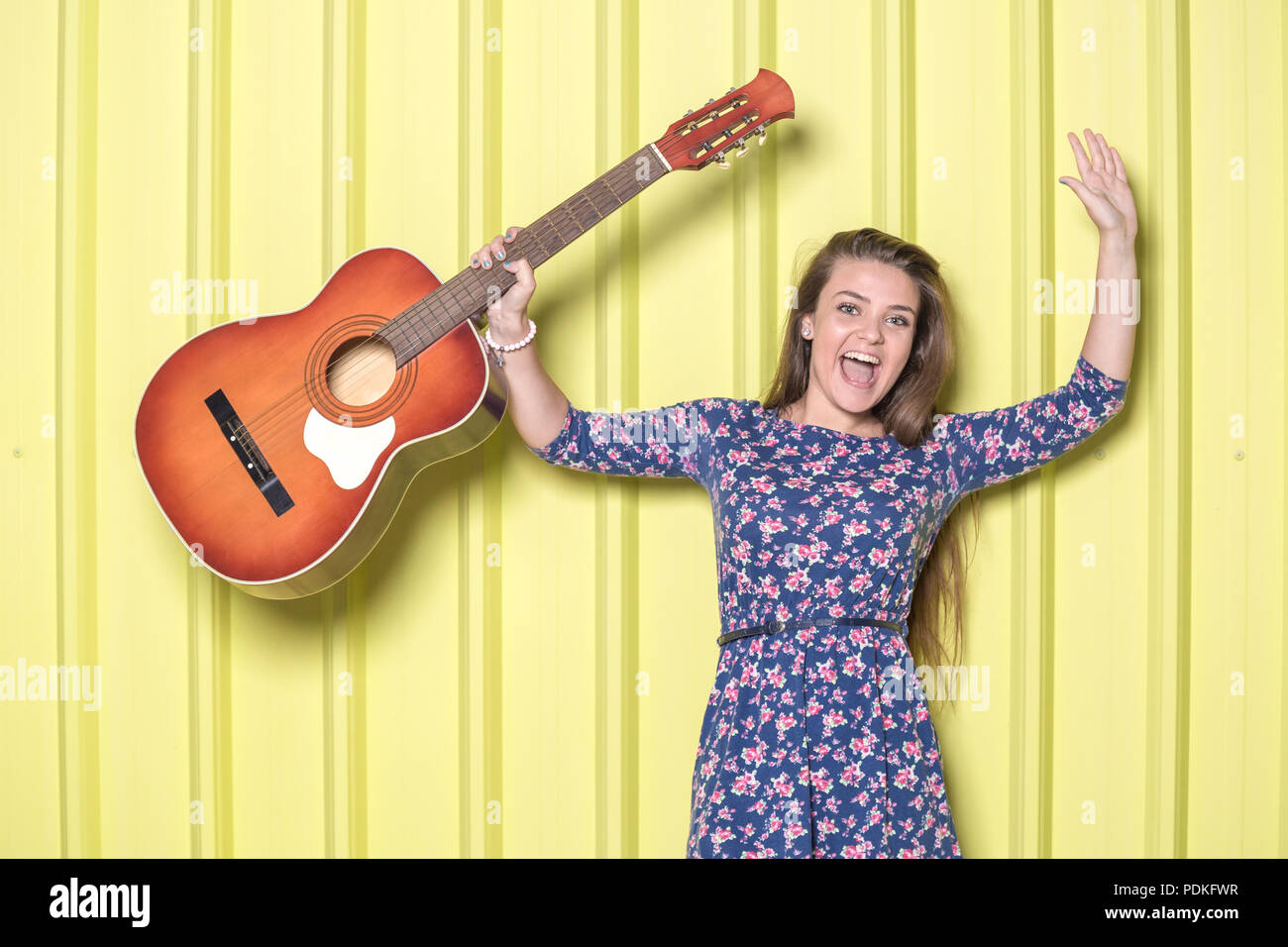 Happy girl holding acoustic guitar on yellow background Stock Photo - Alamy