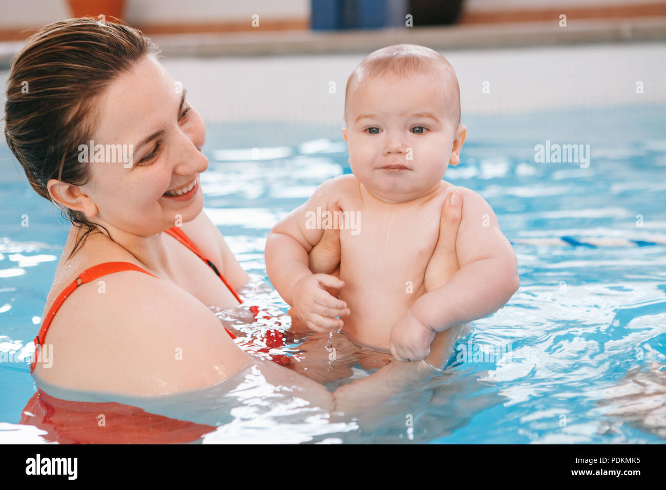 White Caucasian mother traning her newborn baby to float in swimming