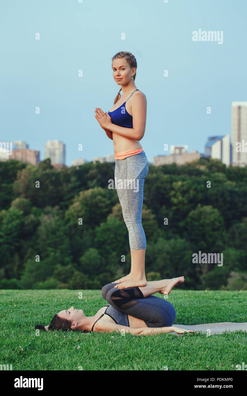 Two young beautiful Caucasian women yogi doing pray acro yoga pose