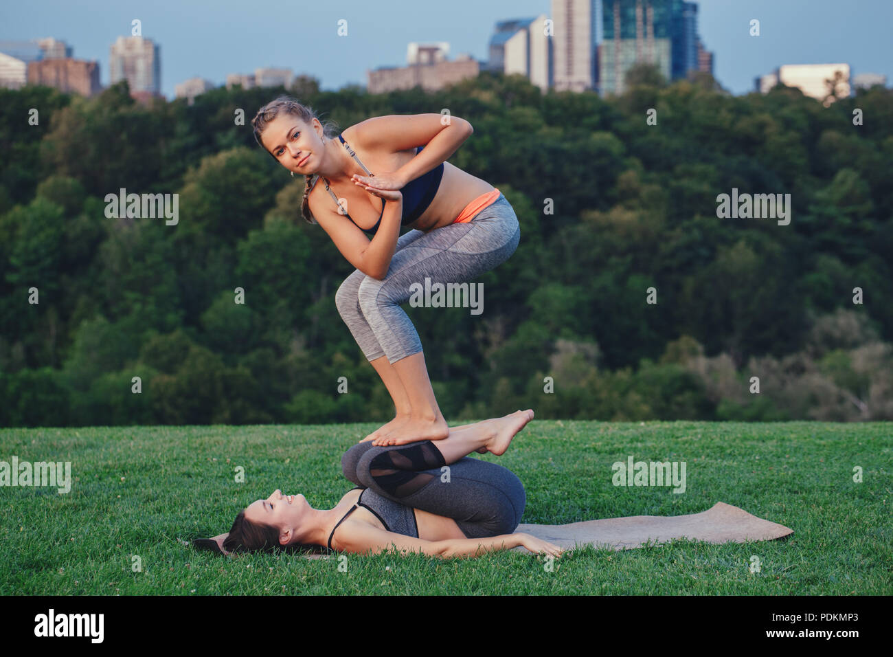 Two young beautiful Caucasian women yogi doing acro yoga pose. Women ...