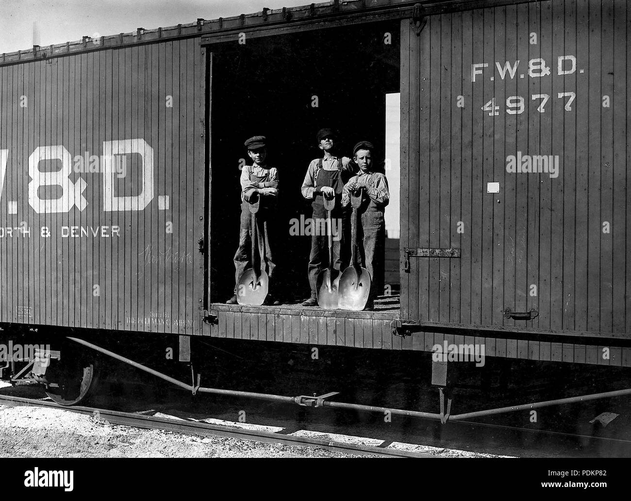 Three young boys with shovels standing in doorway of a Fort Worth & Denver train car, 1912 Stock Photo