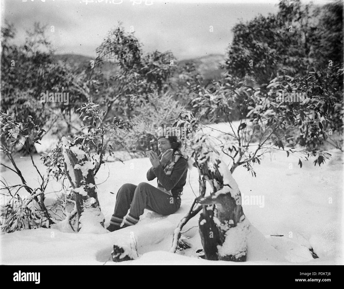 9 A woman skier making up her face amid the snow gums, c. 1930s, by Sam Hood Stock Photo