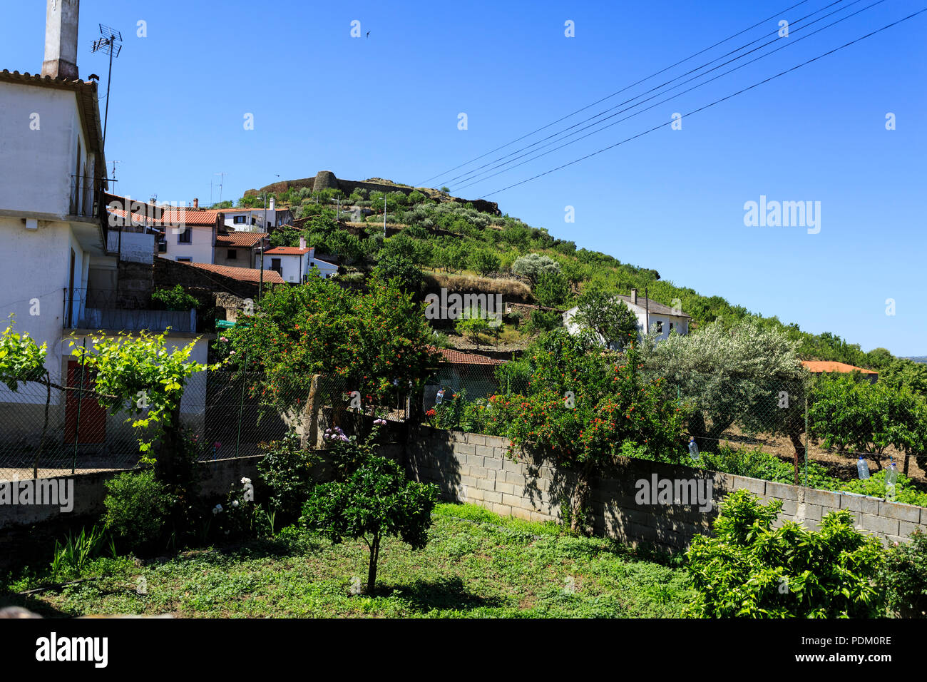 View of the medieval fortress walls of irregular polygonal form circling the hilltop and overlooking the settlement of Castelo Melhor, Portugal Stock Photo
