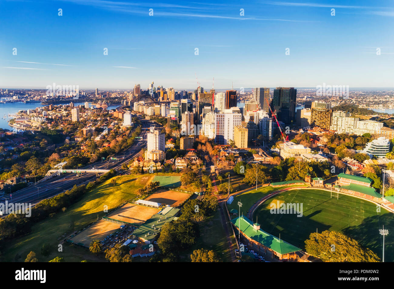 North Sydney from St LEonards park and Oval to distant city CBD across Sydney harbour on a sunny morning under blue sky - aerial elevated view. Stock Photo