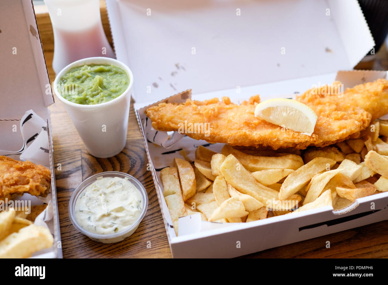 Fish and Chips takeaway with mushy peas and tartar sauce from Longsands Fish Kitchen in Tynemouth Village, Tyne & Wear, England. Stock Photo