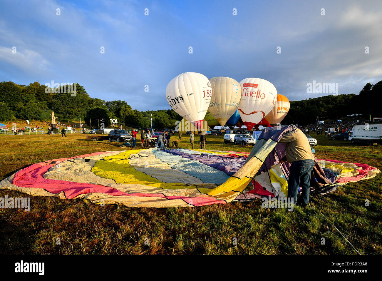 A balloonist unfurls the crown of a balloon canopy as crews inflate for a ground tether flight after bad weather prevented flying at the Bristol International Balloon Fiesta at the Ashton Court Estate in Bristol. Stock Photo
