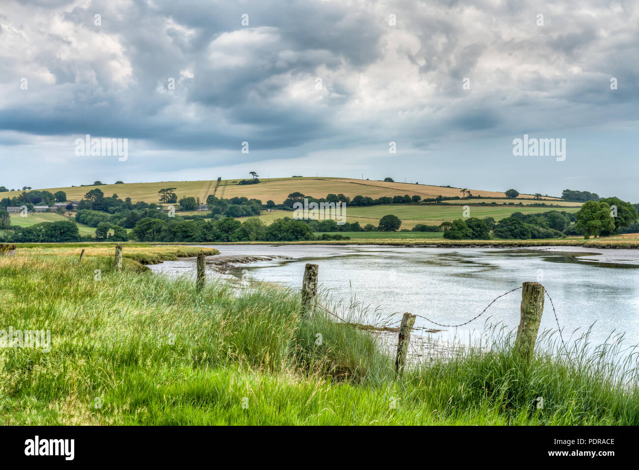 A landscape of the River Lyner which leads off the River Tamar at Plymouth, South Devon. Swirling cloud above sunburnt farmland is in the background. Stock Photo