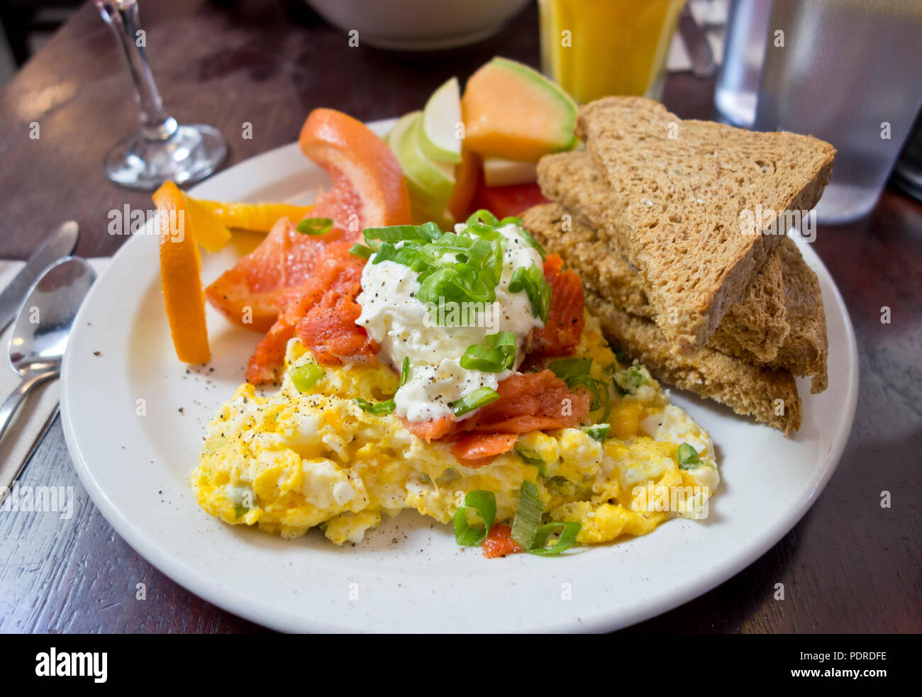 Delicious breakfast with scrambled eggs, smoked salmon,toast, and fruit. Served at Mole Cafe in Victoria, BC, Canada. Stock Photo