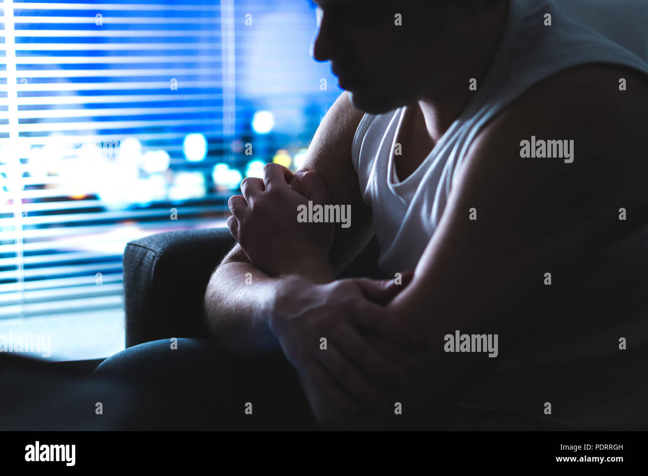 Thoughtful, pensive and contemplating man thinking in dark home at night by the window. Emotional and dramatic mood. Making hard decision. Stock Photo