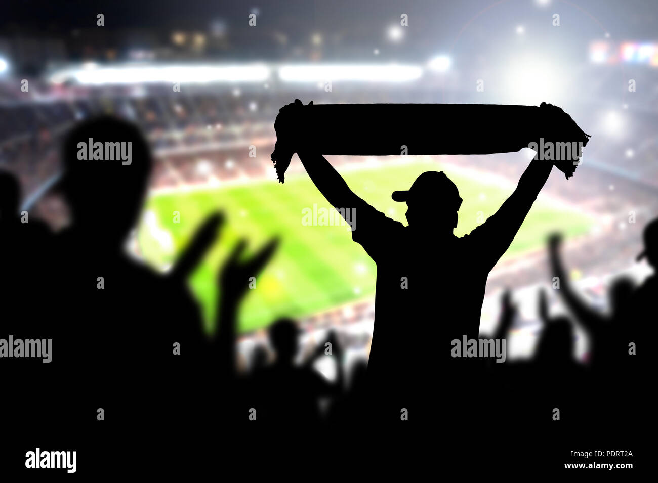 Crowd and fans in football stadium. People in soccer game. Person celebrating goal and holding merchandise scarf for favourite club and team in match. Stock Photo
