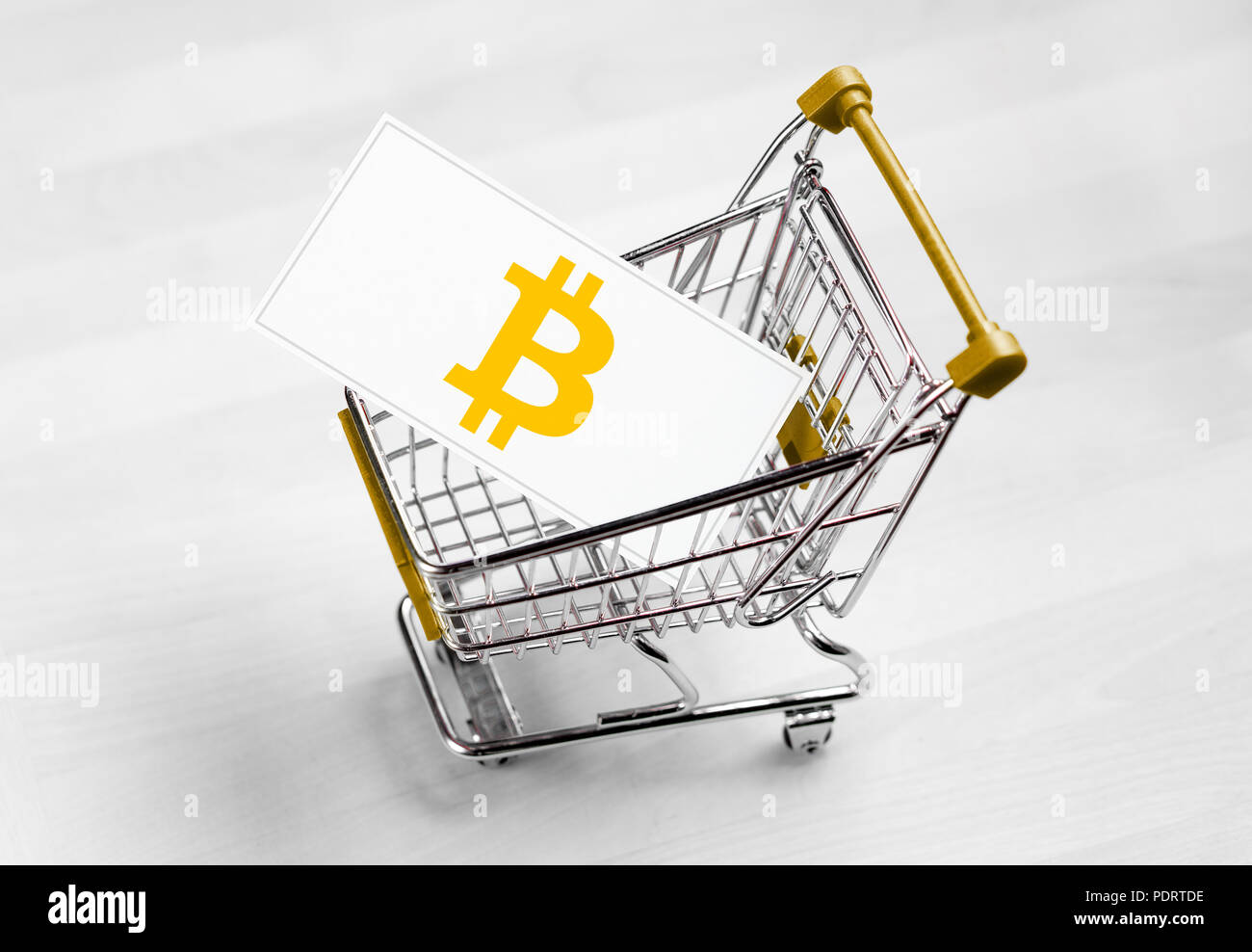 Bitcoin logo on a business card in shopping cart. Buying or selling cryptocurrency concept. Stock Photo