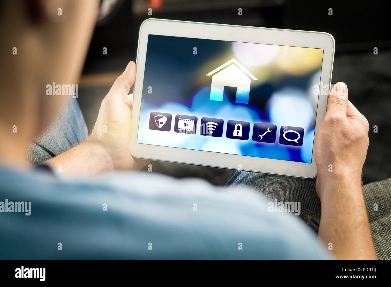 Man using smart home application in tablet to control house appliances. Internet of things (IOT) and remote controller app on smart device. Stock Photo