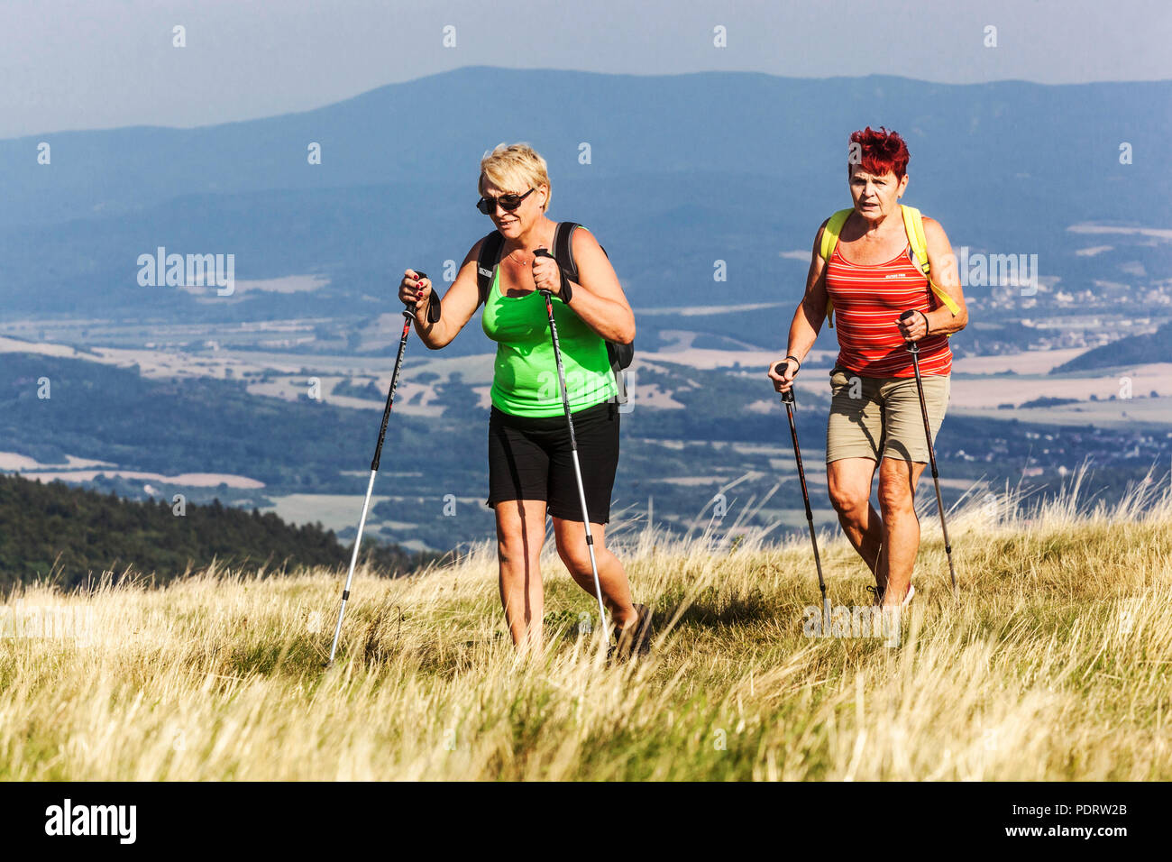 Active aging, Seniors women nordic walking outdoors, keeping fitness, on mountain trail, Velka Javorina, Czech Slovakian border, healthy lifestyle Stock Photo