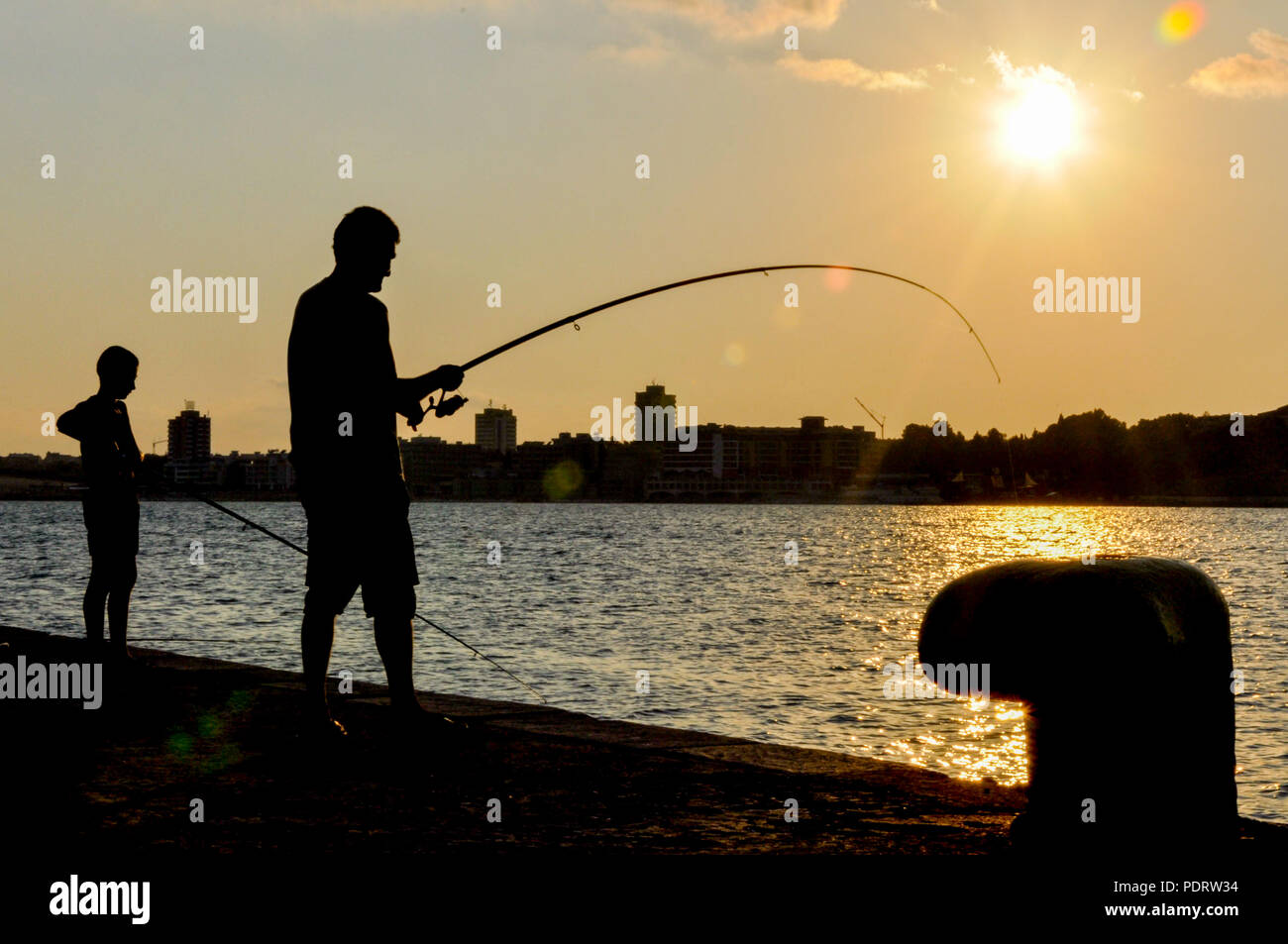 Fisherman silhouette fishing in the sunset Stock Photo - Alamy
