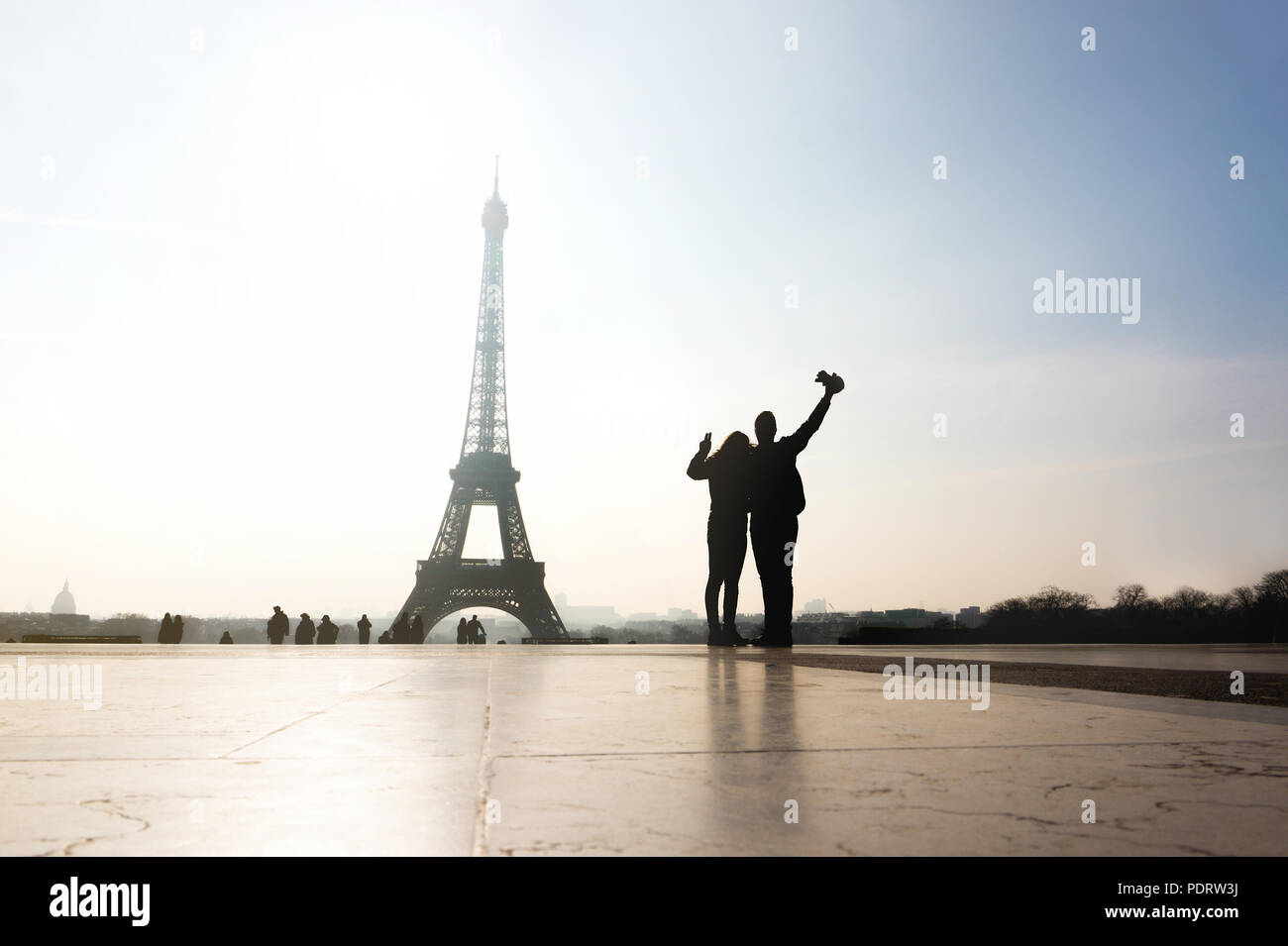 Couple at Eiffel Tower. Travelers and tourists exploring the world and the city of Paris. Romantic lovers on honeymoon or friends having fun. Stock Photo