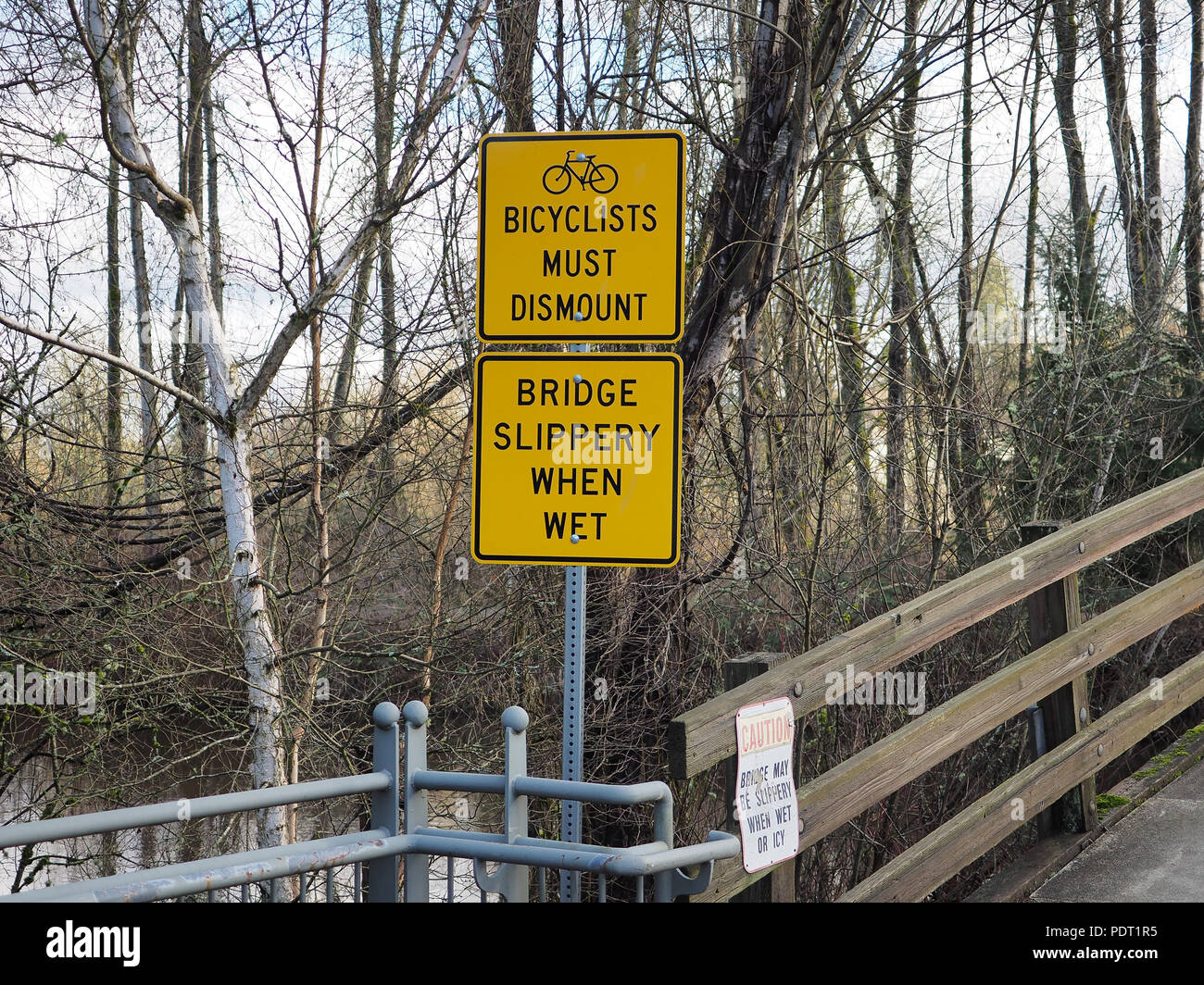 Signs 'Bicyclists must dismount' and 'Bridge slipper when wet' in Bothell, WA, USA Stock Photo