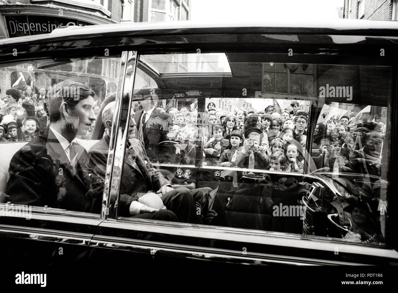 A Brownie pack in Cardigan crowd a street to watch Prince Charles (l) drive past them during the first day of his progress through Wales. *Wirephoto Stock Photo