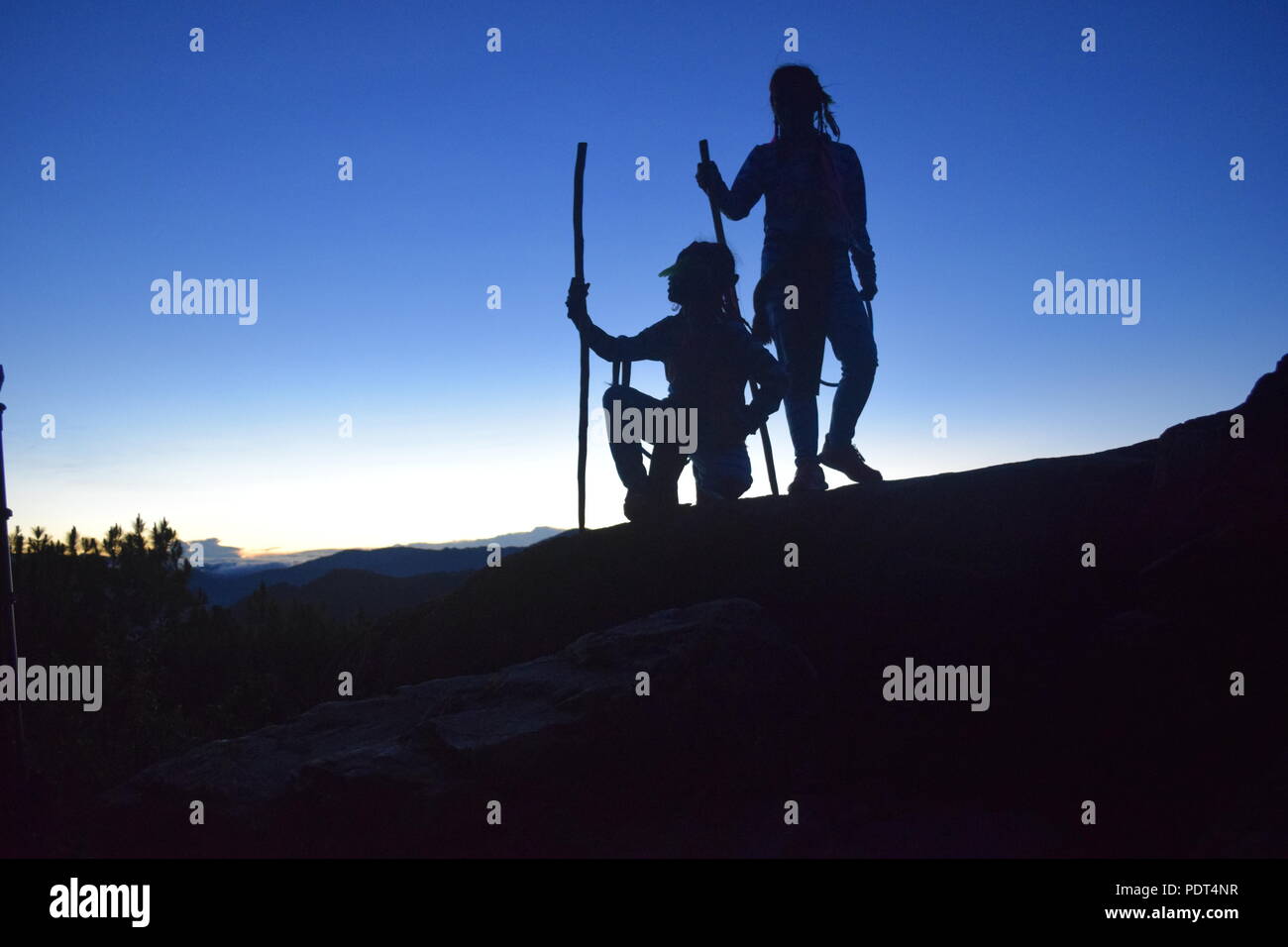 Silhouette Timeline of 2 young girls at the morning dusk standing on top of the Ampucao Sta. Fe ridges awaiting the Sunrise at Mount Ulap in Itogon, Stock Photo