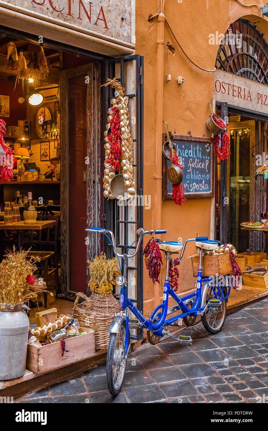 Rome, Italy - October 13, 2016: Old tandem bike decorated with bunches of peppers and garlic in front of an osteria restaurant on a medieval cobblesto Stock Photo