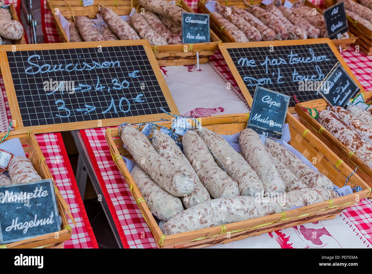 Sausage in a basket on a market stand covered with a traditional red checkered cloth in the Old Town, Vieille Ville in Nice, French Riviera, France Stock Photo