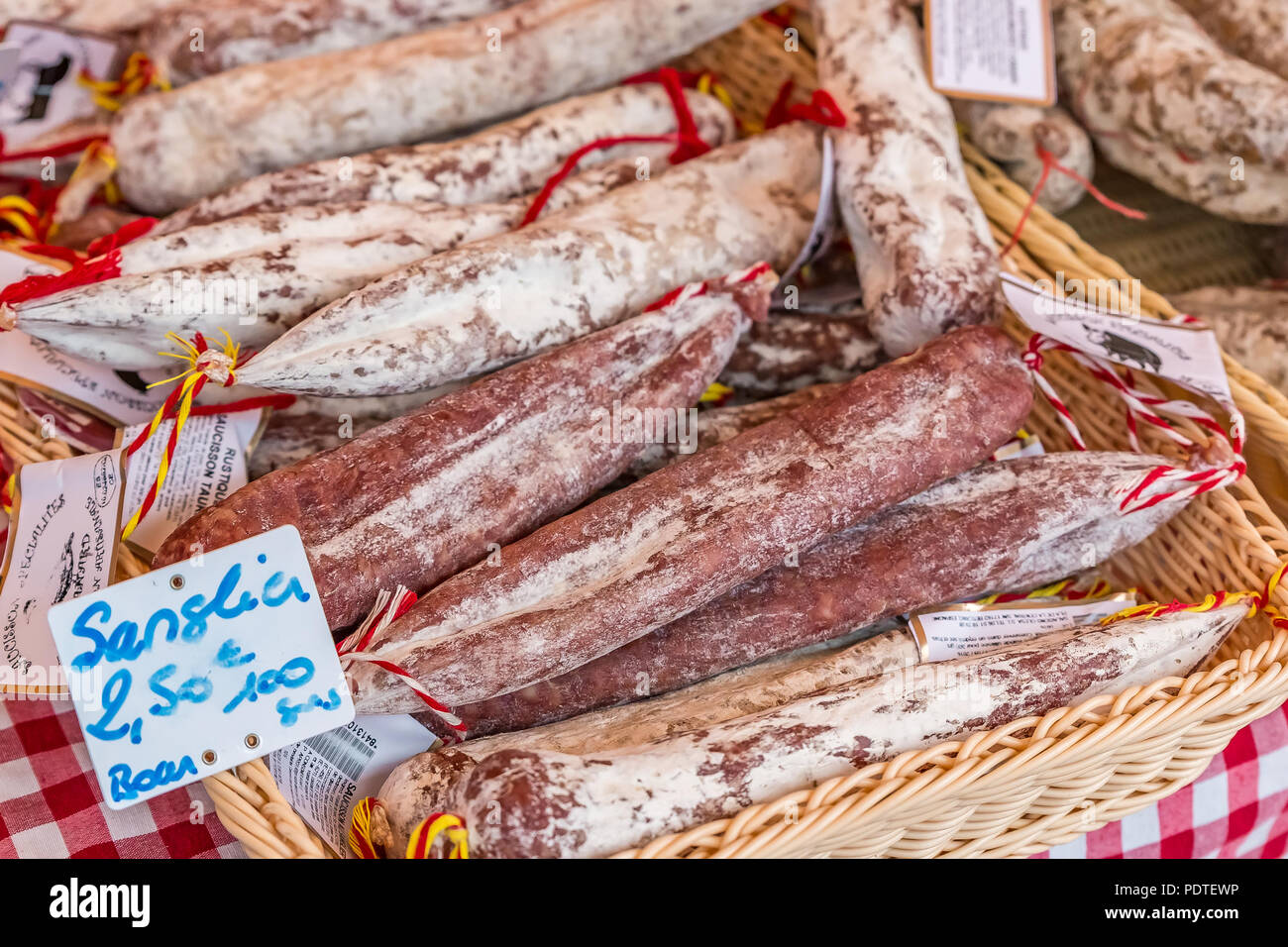 Sausage in a basket on a market stand covered with a traditional red checkered cloth in the Old Town, Vieille Ville in Nice, French Riviera, France Stock Photo