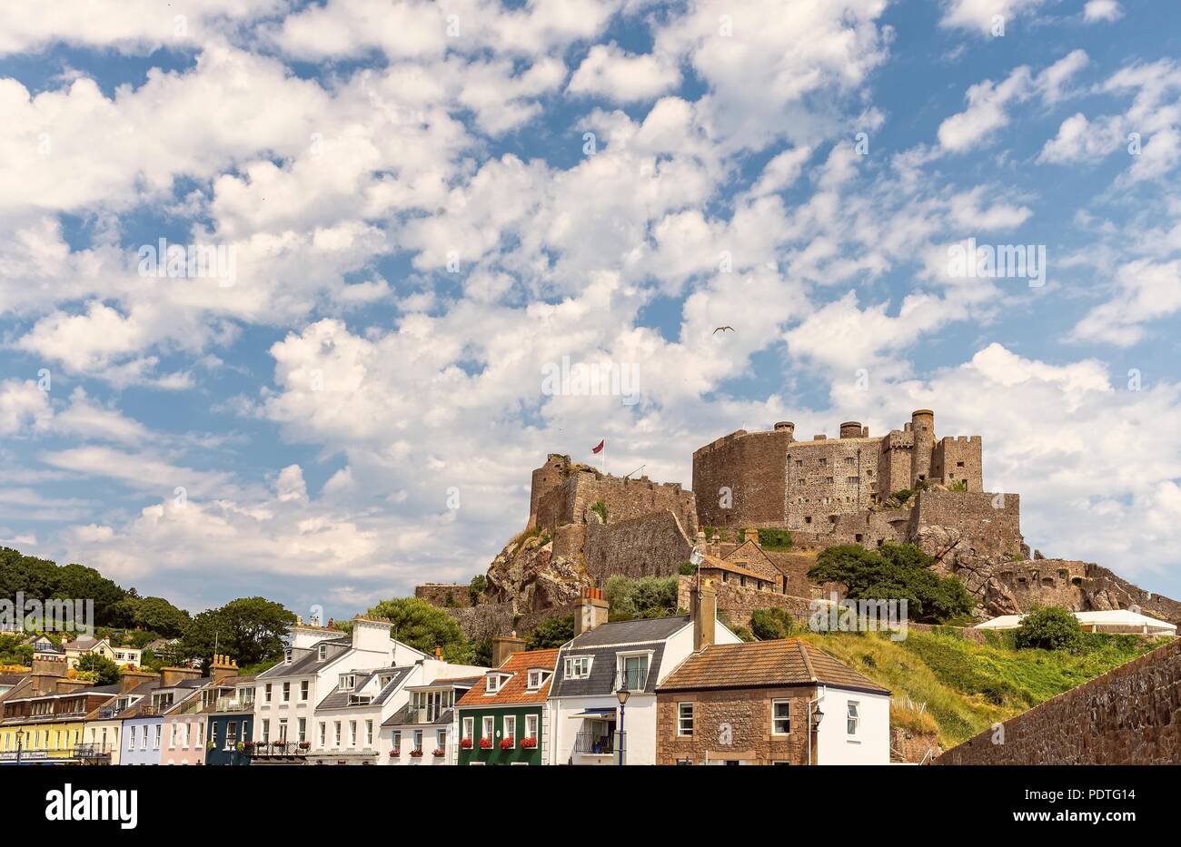Gorey (Mont Orgueil) Castle in Jersey. Buildings are nestled below and a  sea wall is in the foreground Stock Photo - Alamy