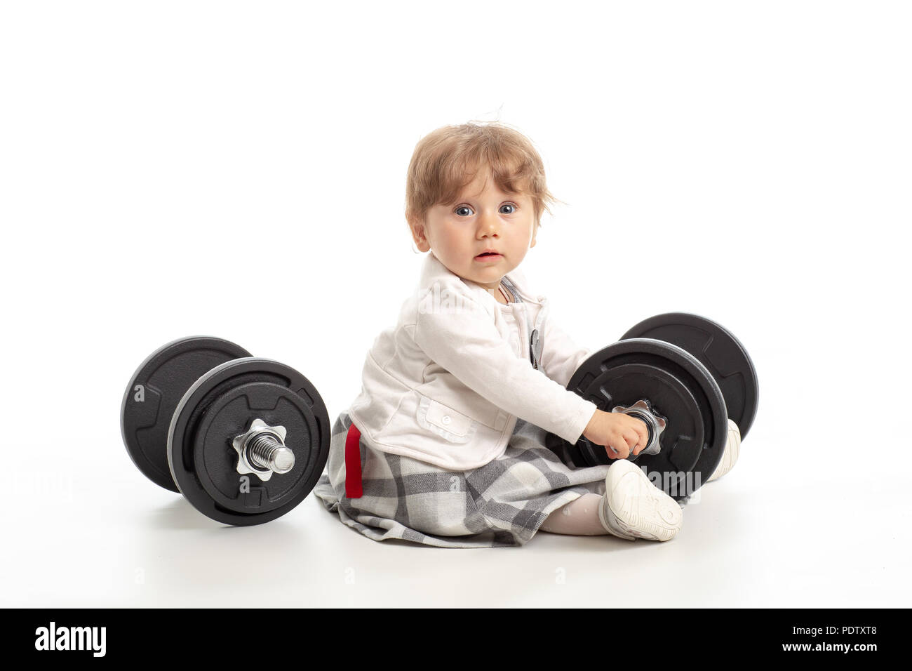 Small female baby playing with gym weights in studio shot on white background. Concept healty life in gym Stock Photo