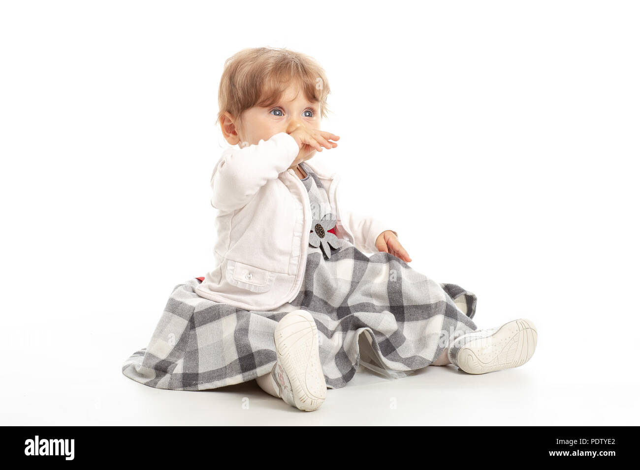 Elegant baby girl 1 year old sitting on the studio floor. White Background. Stock Photo