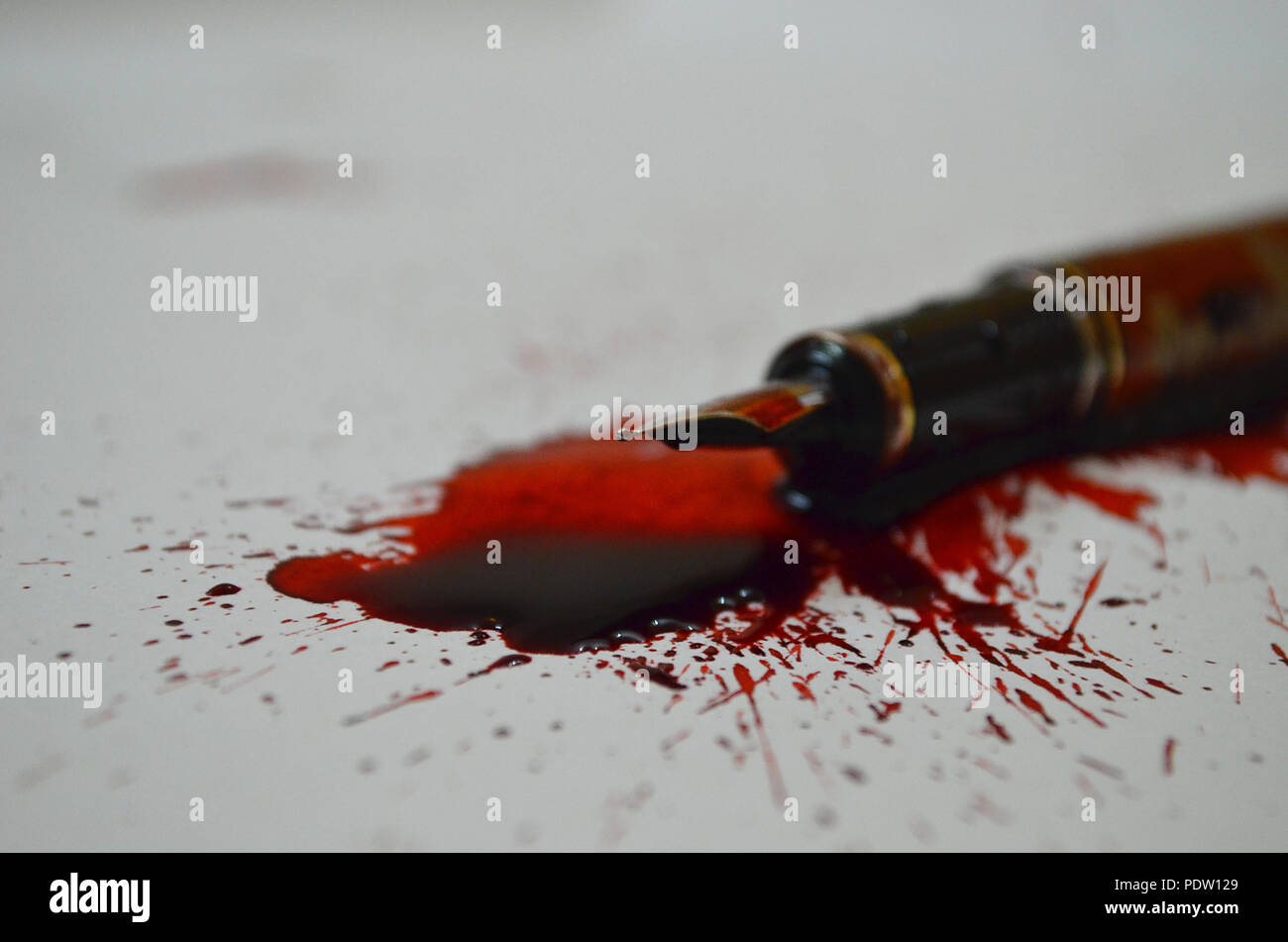 Pen and spilled red ink depicting that a pen is mightier than a sword Stock Photo