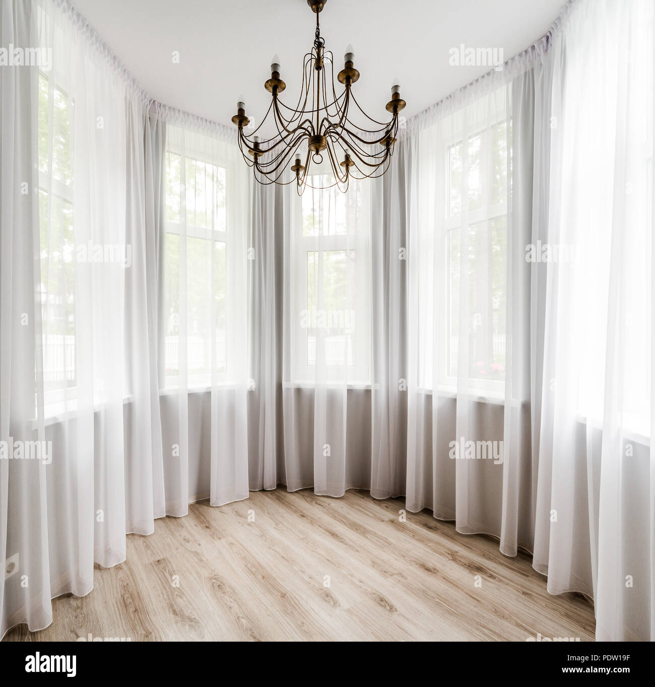 Elegant room interior with wooden floor, white curtain and chandelier