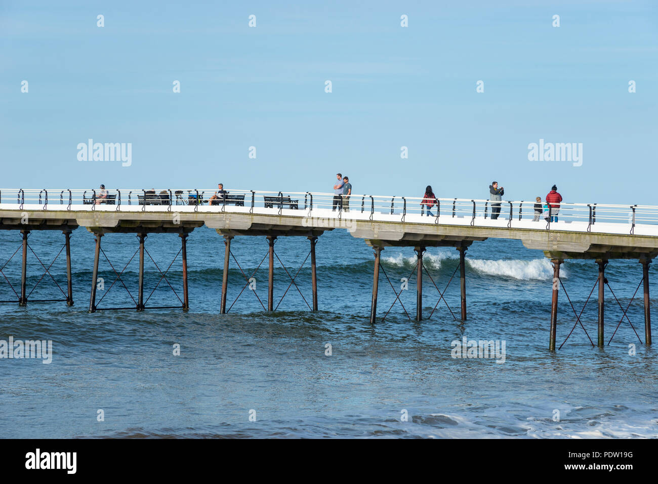 People enjoying a stroll along the old pier at Saltburn-by-the-sea on the coast of North Yorkshire, England. A lovely spring evening. Stock Photo