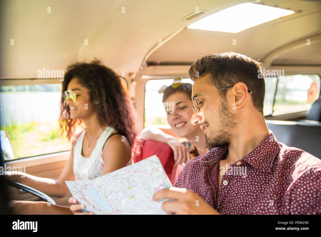 Mixed group of happy young people going on holiday in a van Stock Photo