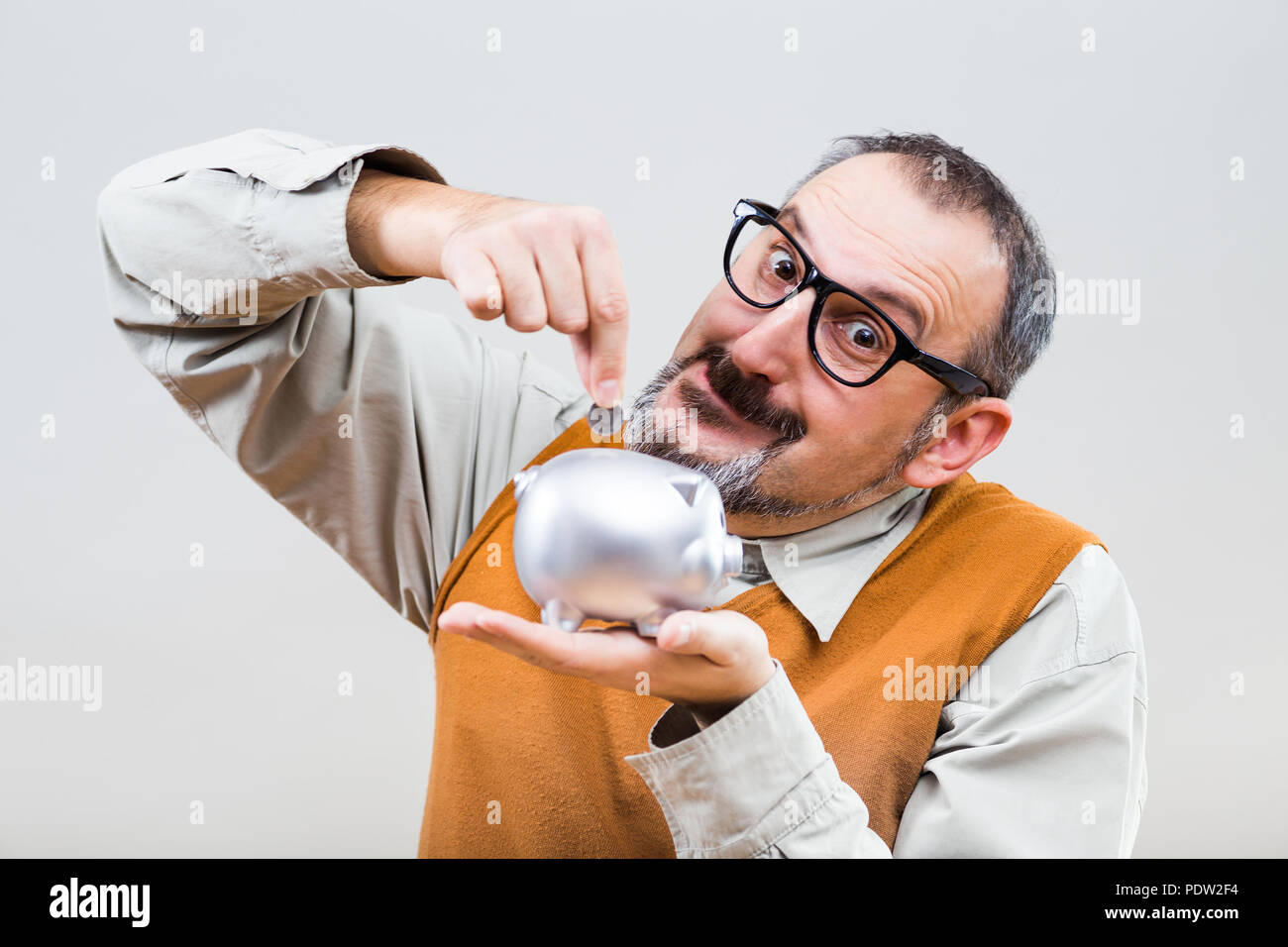 Nerdy man is putting coin into piggy bank. Stock Photo