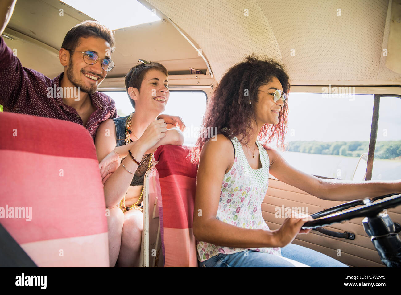 Mixed group of young people going on holiday in a vintage van Stock Photo