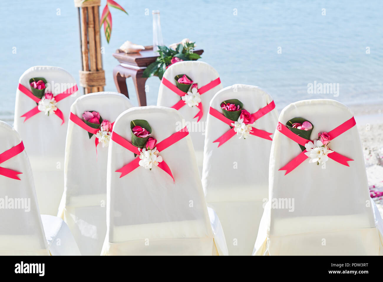 Back side of a group of white spandex wedding chairs cover with red