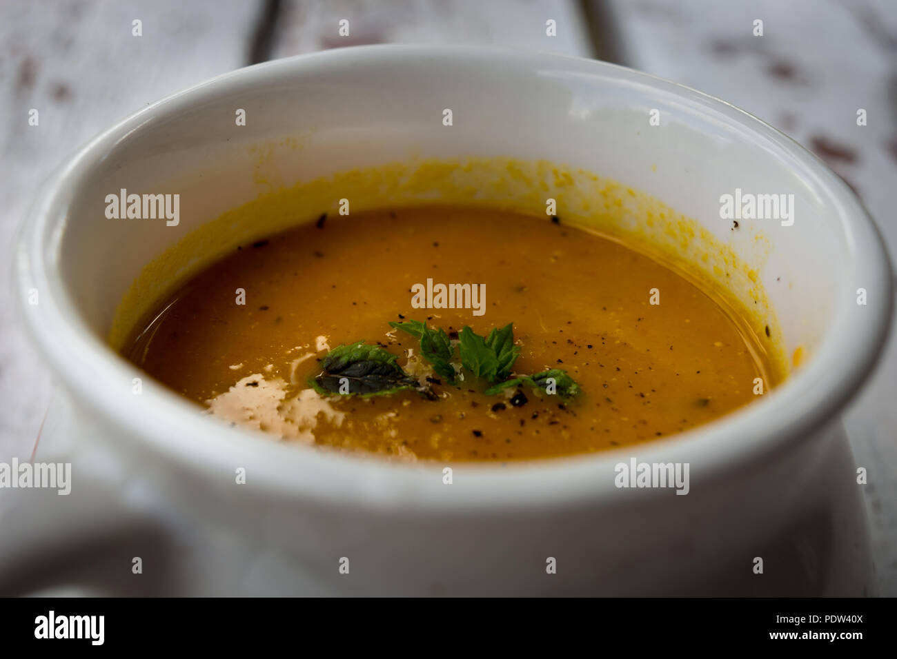Soup with carrots, ginger and orange juice decorated with mint Stock Photo