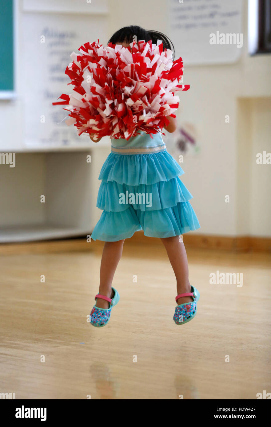 A four year old girl participates in a cheerleading class. Stock Photo