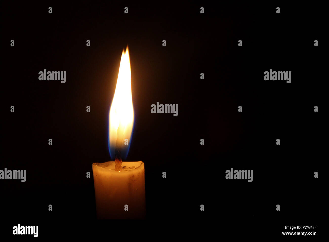 A candle illuminating the darkness Stock Photo
