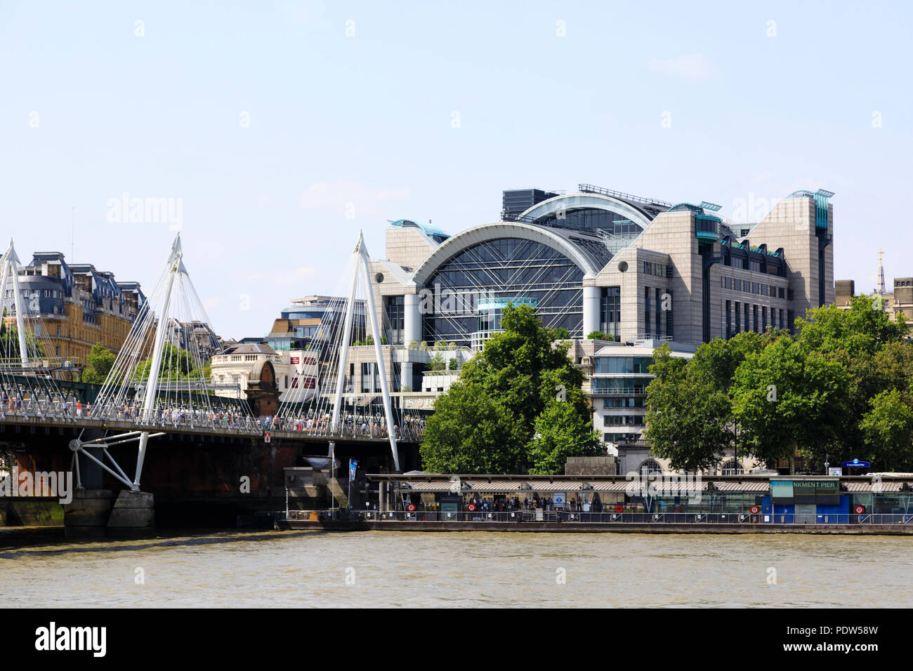 Charing Cross railway station on the north bank of the River Thames, London. Hungerford and Golden Jubilee bridge with crowds of tourists. Stock Photo