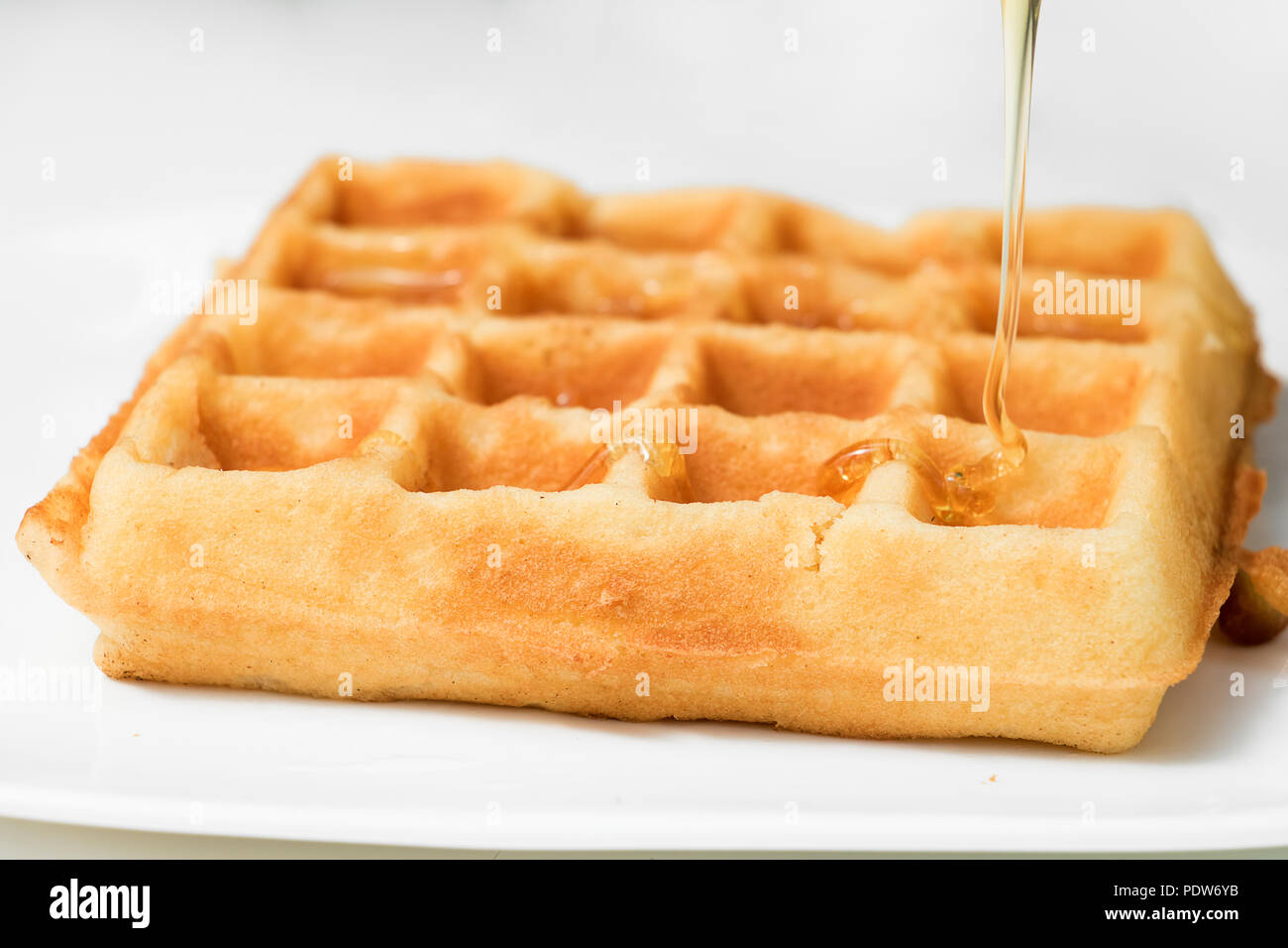 A pouring golden honey on fresh waffle, close up Stock Photo - Alamy
