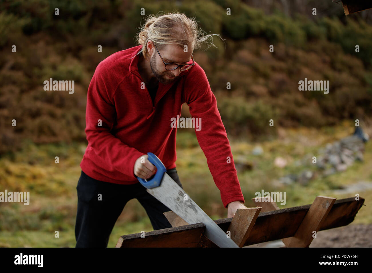 A man cutting wood in a real location Stock Photo