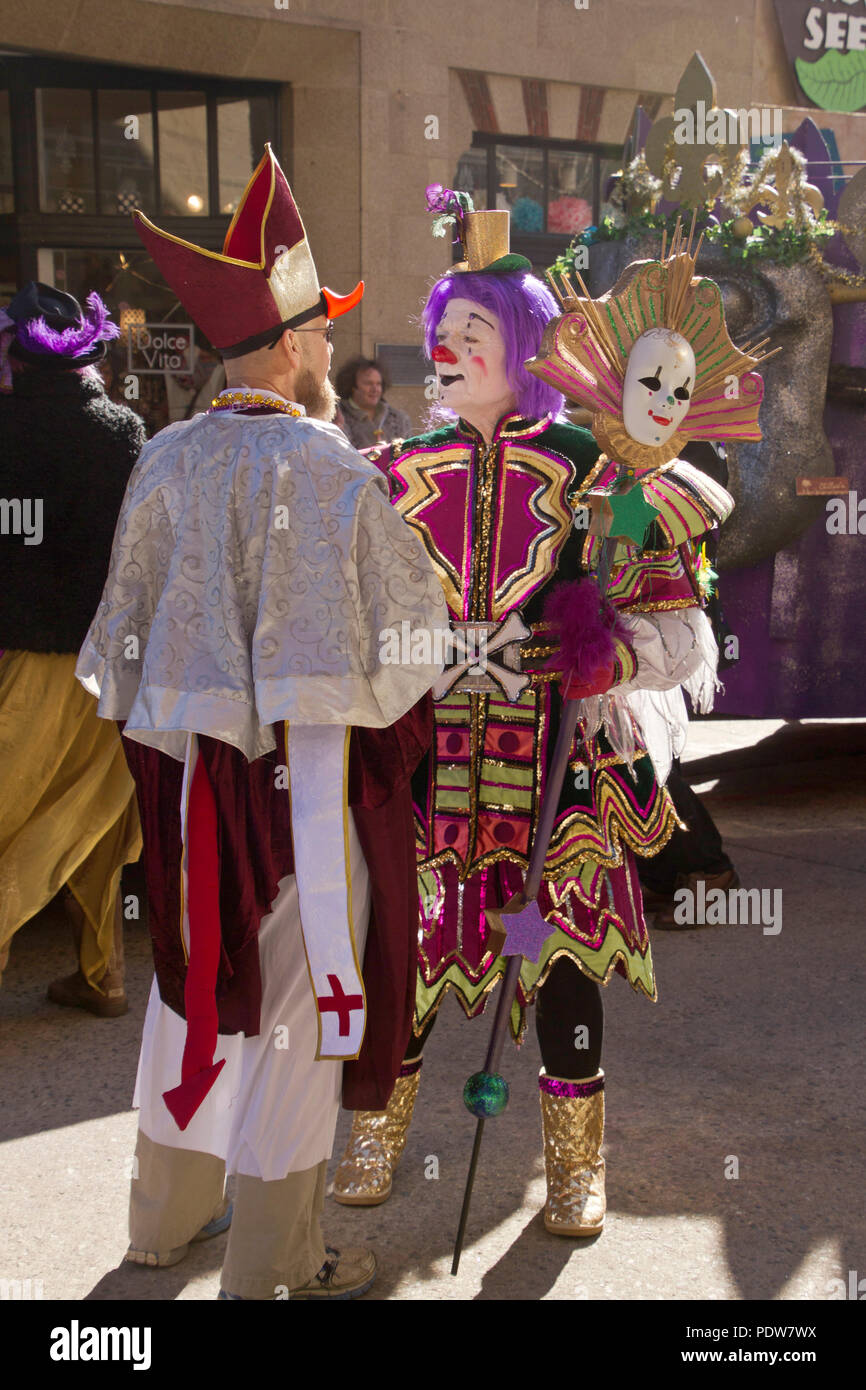 ASHEVILLE, NORTH CAROLINA, USA - FEBRUARY 7, 2016: A colorful and creatively costumed Mardi Gras clown converses in the street with a costumed Bishop  Stock Photo