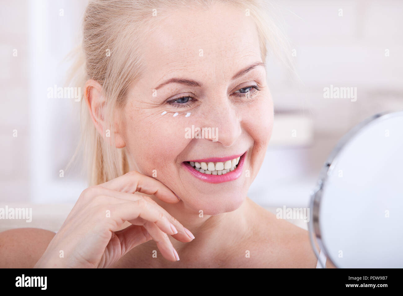 Middle aged woman looking at wrinkles in mirror. Plastic surgery and collagen injections. Makeup. Macro face. Selective focus on the face. Realistic i Stock Photo