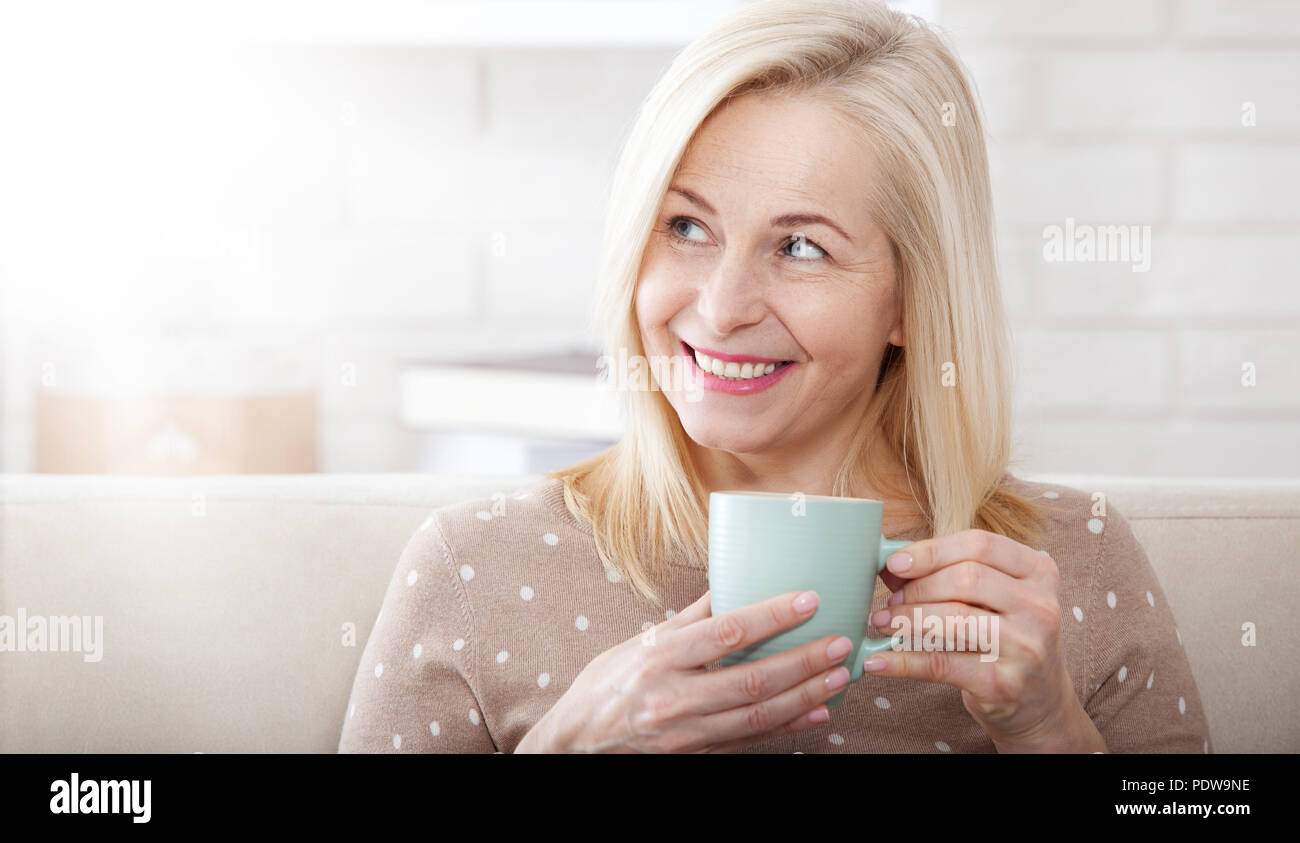 Portrait of happy middle aged woman with mug in hands Stock Photo